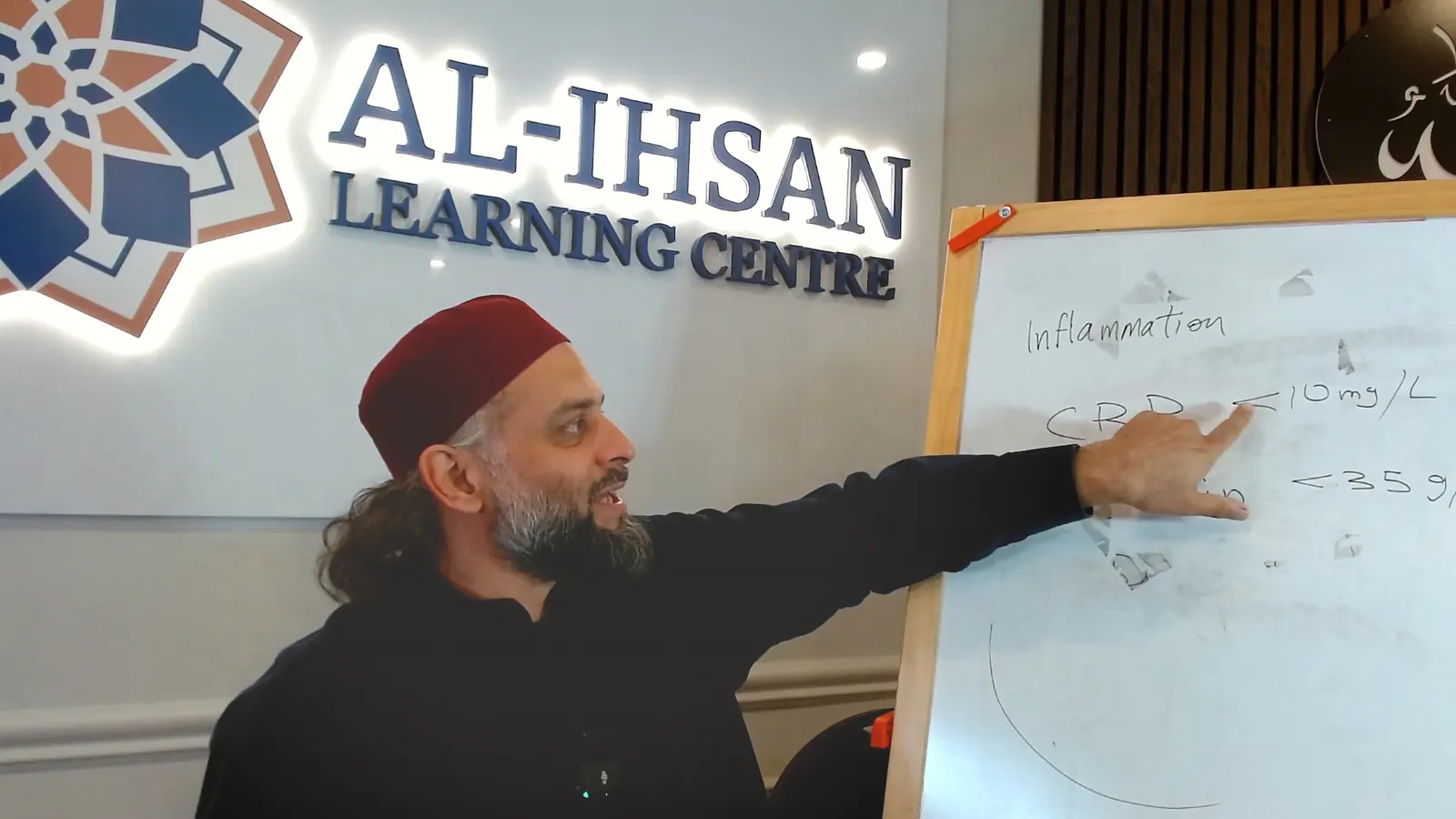 Dr. Rehan Zaidi pointing to inflammation markers on a whiteboard at Al-Ihsan Learning Centre